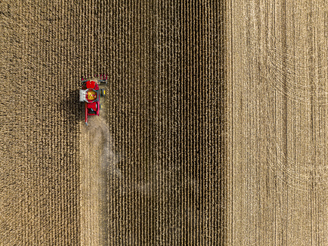 Aerial View of Tractor and Agricultural Machinery Harvesting corn field, Quebec, Canada.