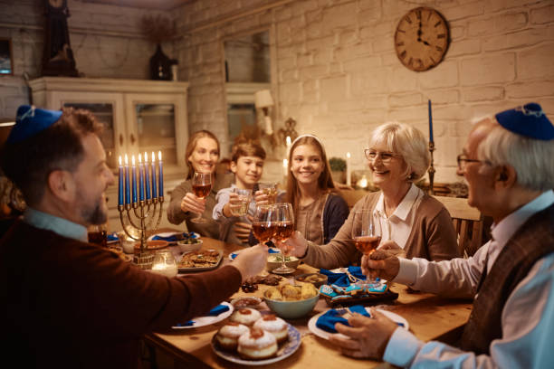 istock Happy extended family celebrating Hanukkah and toasting while having dinner at dining table. 1436772337