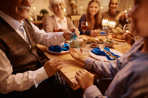 close up of senior man giving hanukkah gelt to his grandson while celebrating jewish festival of lights. - gelt imagens e fotografias de stock