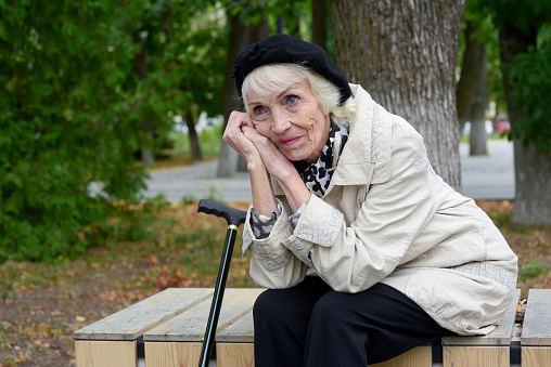 Pretty, pensive elderly lady with gray hair on a walk in the park.