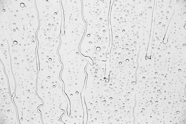 istock Drops of rain on glass against blue sky and white clouds. 1436775811