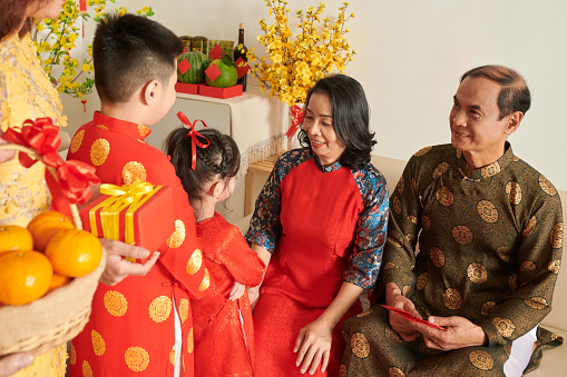 Grandfather and grandmother accepting Lunar New Year presents from grandchildren
