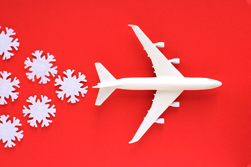 a plane with snowflakes on a red background. travel concept for New Year holidays or winter resorts.