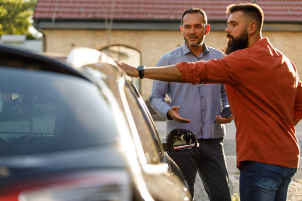 Salesman showing a car to a customer, sharing performances while inspecting the vehicle stock photo