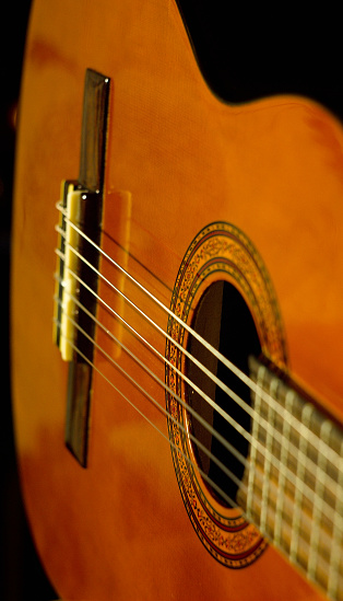 Wooden Spanish guitar on musical background.