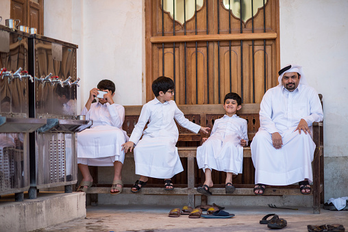 Doha, Qatar- March 05, 2019 : The Qatari family in traditional attire hang out in old bazaar market Souk Waqif.