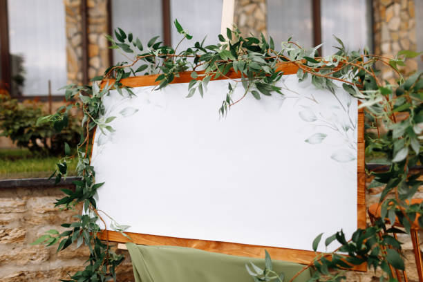 istock Wedding wooden board, mockup, invitation easel, with white space for an inscription, decorated with fresh greenery and green cloth. Wedding frame outdoors. Festive decor, copy space. 1436793312