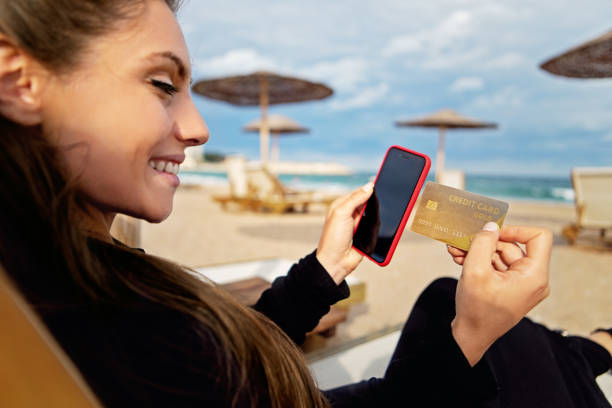 istock Woman is shopping online/making reservation on a beach 1436794832