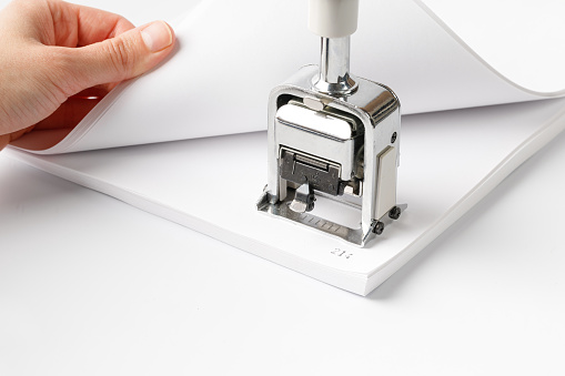 Woman stamping page numbers. To number the pages, automatic numbering system for paper. Office supplies, stationery. Stamp for numbering of documents