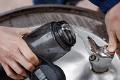 Close up on a woman's hands filling a water bottle at an outdoor water fountain in a park.