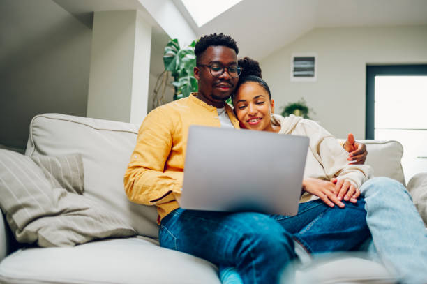 istock Multiracial couple using laptop while sitting on a sofa at home 1436805744