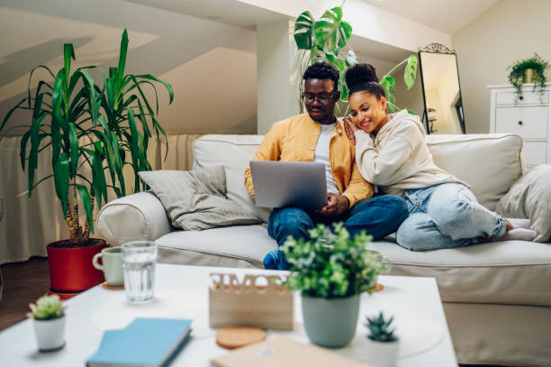 istock Multiracial couple using laptop while sitting on a sofa at home 1436805775