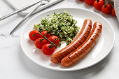 Two fried sausages and Rice with Spinach and microgreens on white plate. Dinner dish idea.