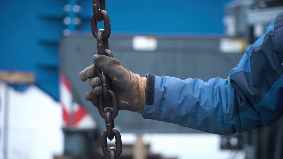 Worker touches the crane hooks to the loops during repair work. Clip. Worker keeps the chain of the crane.