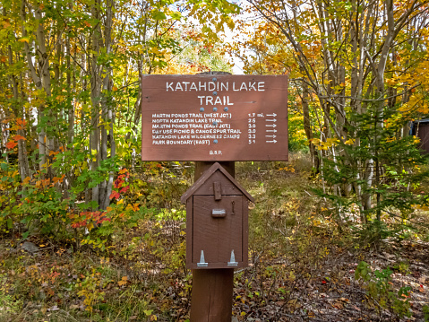 Katahdin Lake Trail sign includes nearby hiking trails and distances in early fall from Lake Katahdin, Maine, in early fall