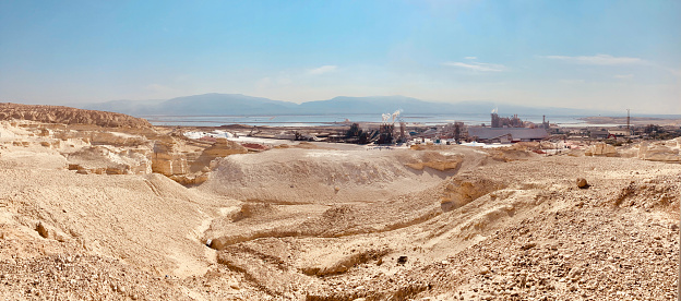 Dead Sea landscape with mineral power facility in Israel. Harsh landscape view of coastal area of the water form during the day.