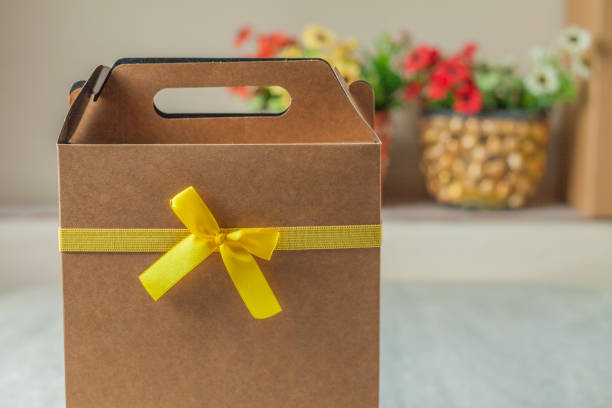 istock Gift wrapping with a yellow bow and flowers in the background. 1436830307