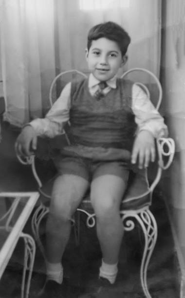 imagem em preto e branco tirada nos anos 50: menino sorridente sentado em uma cadeira olhando para a câmera - 1955 - fotografias e filmes do acervo