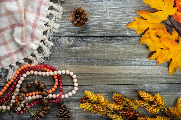 Autumn flatlay concept, with dried flowers, coral pink jewelry beads, plaid towel, and pine cones on a wood background stock photo