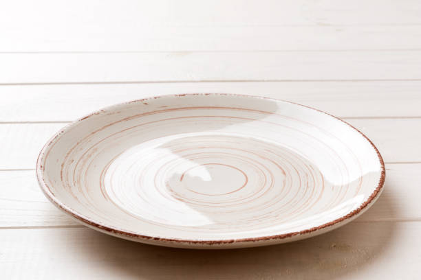 istock Perspective view of empty colorful plate on wooden background. Empty space for your design 1436834354