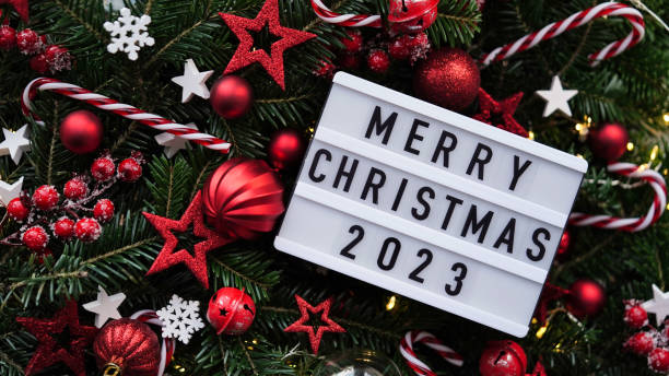 Marry Christmas banner concept.White board with text Happy Xmas 2023 among Christmas red decor,balls,berries, striped candy canes,tree branches,snowflakes,stars on red background,top view,flat lay. cásate con el concepto de banner navideño. pizarra blanca con texto feliz navidad 2023 entre decoración roja navideña, bolas, bayas, bastones de caramelo rayados, ramas de árboles, copos de nieve, estrellas sobre fondo rojo, vista superior, plano