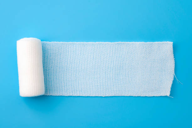 First aid, injury protecting wrapping and wound dressing concept clean cotton gauze bandage isolated on blue background with copy space First aid, injury protecting wrapping and wound dressing concept clean cotton gauze bandage isolated on blue background with copy space wrap dress stock pictures, royalty-free photos & images