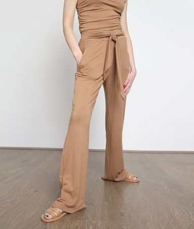 Studio shot of woman in beige cotton casual outfit, sleeves shirt and basic pants.
