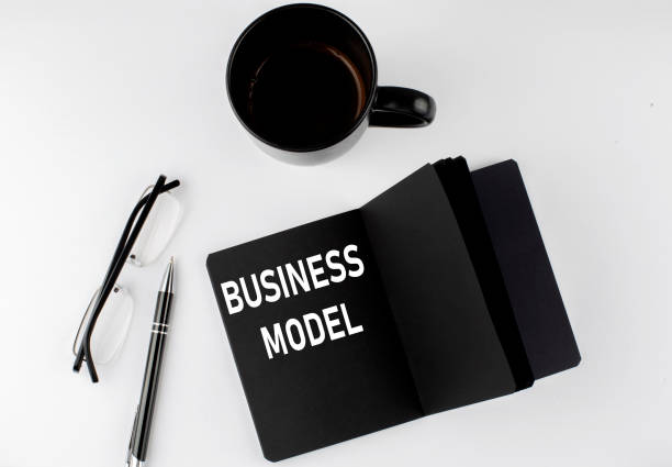 istock BUSINESS MODEL written text in small black notebook with coffee , pen and glasess on a white background. Black-white style 1436848948