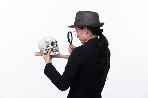 Detective female hold magnifying confident investigate cause of death, white background isolated. Half body 20s Asian Woman wear black business suit tie dress hat glasses, search investigate truth