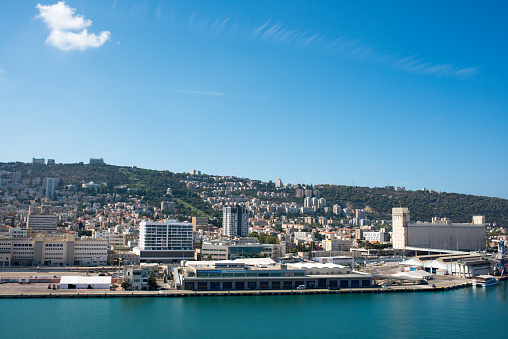 Haifa, Israel - Oct 10, 2022:  Port of Haifa , one of the three major international seaports in Israel, serves both passenger and merchant ships.  Baha'i Gardens is visible in the landscape background.