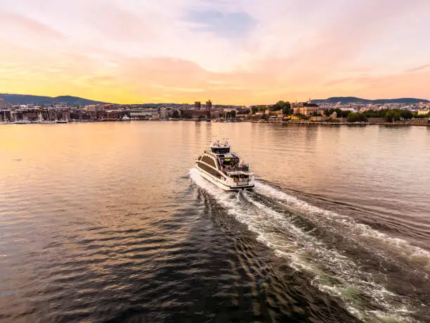 Electrical battery operated ferry at Oslo Fjord at sunset with Oslo City Skyline in the back , 4k resolution