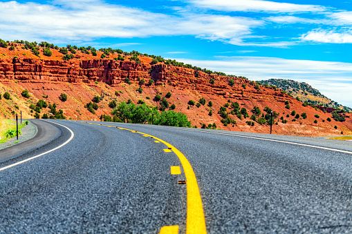 Red cliffs along a curved roadway through the wilderness of Wyoming, USA.