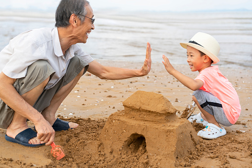 Grandpa and grandson digging sand by the sea