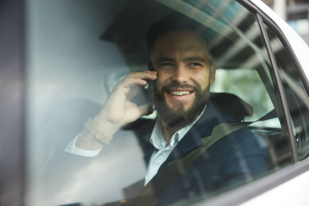 istock Smiling businessman talking on a phone while riding in a taxi 1436876366