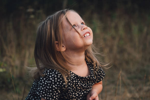 Portrait of a beautiful blonde little European girl with blue eyes in nature. A small child dreamily and wonderingly looks at the sky, close-up. Sincere children's emotions Portrait of a beautiful blonde little European girl with blue eyes in nature. A small child dreamily and wonderingly looks at the sky, close-up. Sincere children's emotions. wonderingly stock pictures, royalty-free photos & images