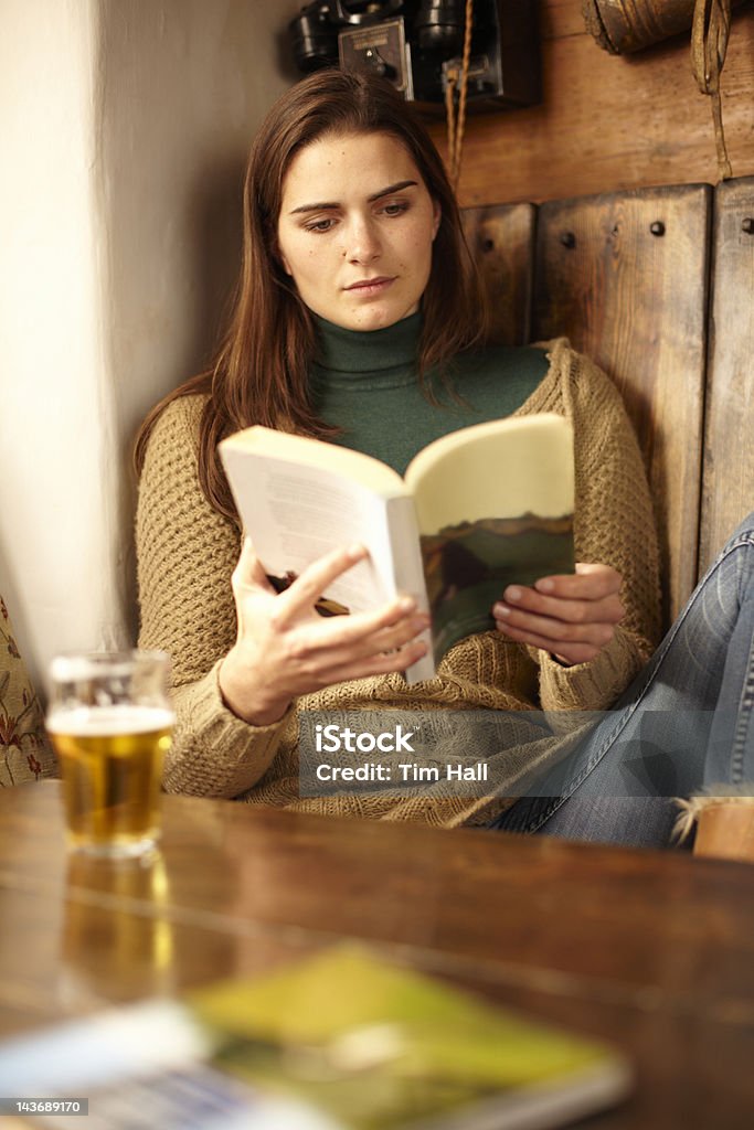 Mulher lendo com uma cerveja no pub - Foto de stock de Ler royalty-free