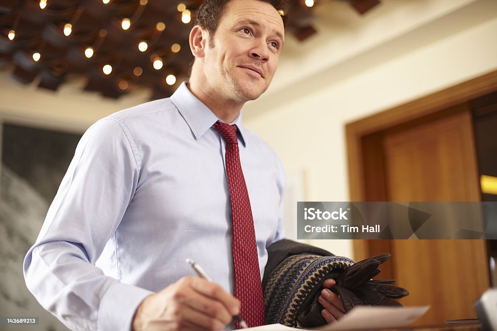 Businessman writing at hotel front desk  Business Travel Stock Photo