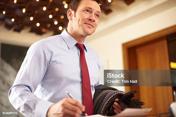 Businessman Writing At Hotel Front Desk Stock Photo - Download Image Now - Business Travel, Hotel, 30-39 Years