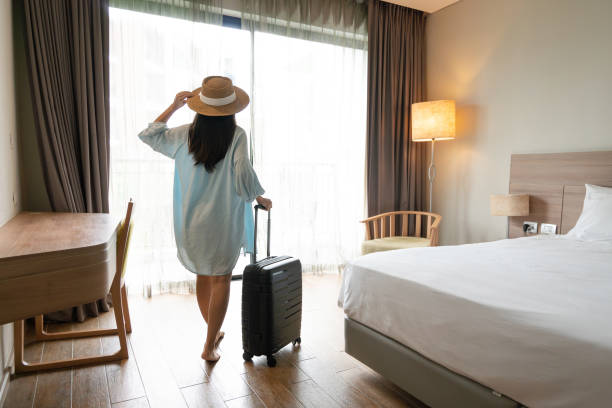 Young Asian traveler woman with luggage and straw hat in hotel room after check-in. Travel and summer holiday concept. Copy space Young Asian traveler woman with luggage and straw hat in hotel room after check-in. Travel and summer holiday concept. Copy space hotel suite stock pictures, royalty-free photos & images