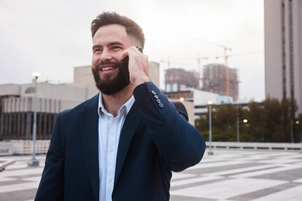 istock Young businessman smiling and talking on his phone outside after work 1436897543