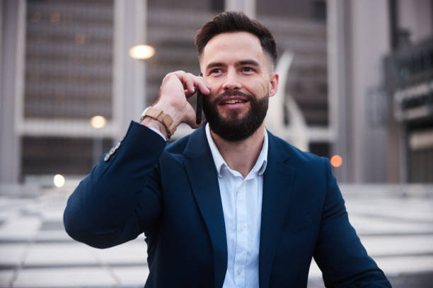 istock Smiling businessman talking on his phone outside an office building 1436897606