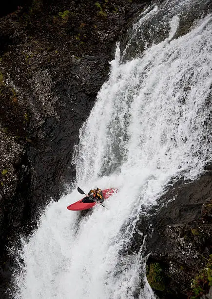 Photo of Man canoeing over rocky waterfall