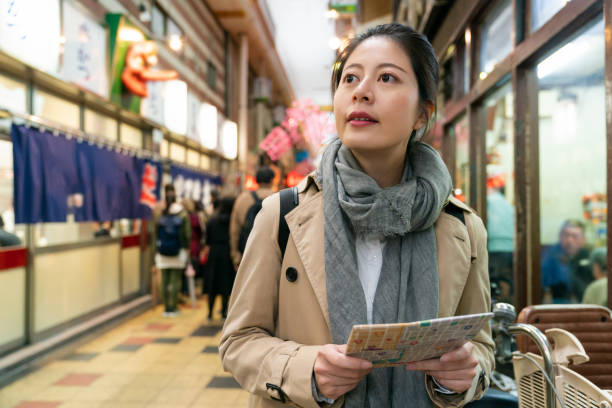 istock curious Asian Japanese female traveler looking into distance while using guide map to search for restaurant in the arcade food street in Shinsekai area of Osaka Japan 1436898935