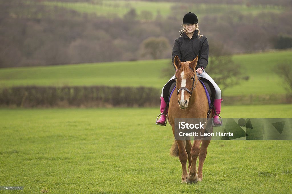 Teenage girl riding horse in field  Horseback Riding Stock Photo