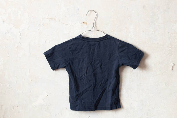istock dark blue t-shirt on hangers on an old white wall 1436902041