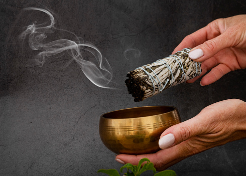 white sage incense and singing bowl in front of white background