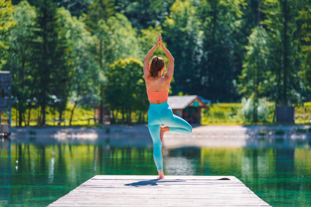 istock Woman In Yoga Tree Pose On Pier Overlooking Lake 1436906428