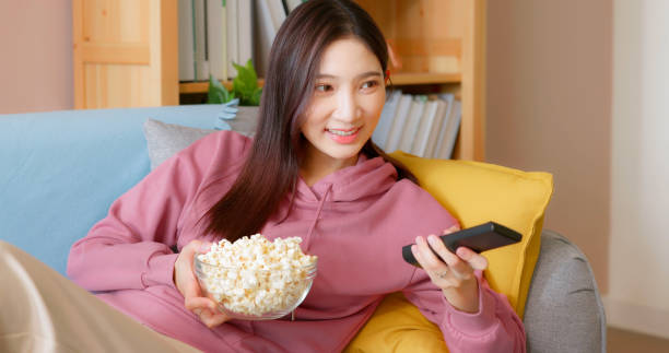 istock woman eat popcorn on couch 1436907560