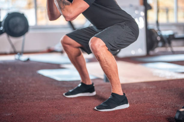 Focused Caucasian Male Athlete doing Squats at Gym