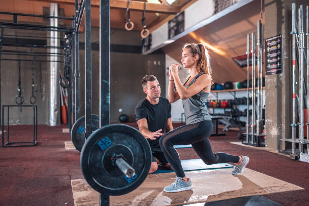 istock Instructor looking at female athlete doing lunge 1436909125